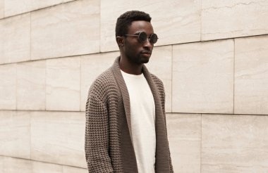 Şehrin arka planında izole edilmiş örgü bir hırka giymiş şık, genç bir Afrikalı adamın portresi.