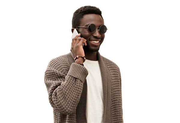 白い背景に孤立したスマートフォンで話している若いアフリカ人男性の笑顔の肖像画 — ストック写真