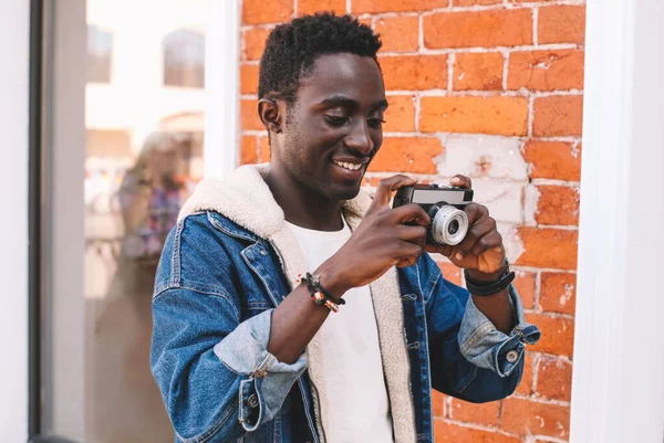带着老式摄像机在城市街道上拍照的快乐微笑的非洲男性摄影师的画像 — 图库照片