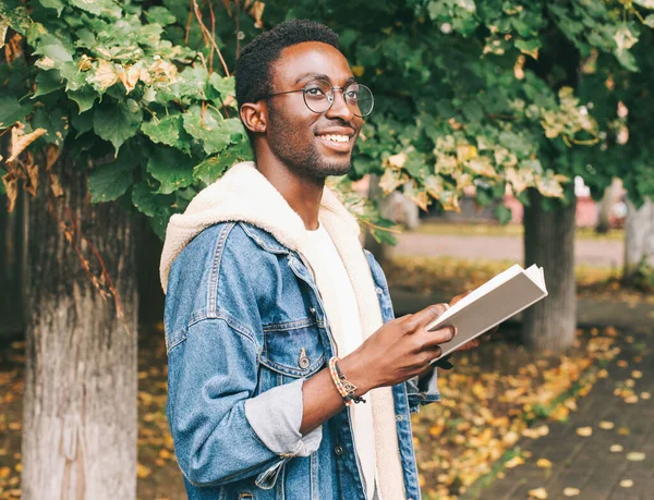 Sonbahar Parkında Gözlük Takmış Elinde Kitap Olan Afrikalı Genç Bir - Stok İmaj