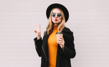 Tarz sahibi genç bir kadının şık portresi. Kahve fincanı ile dudaklarını kırmızı rujla siliyor. Barış öpücüğü yolluyor.