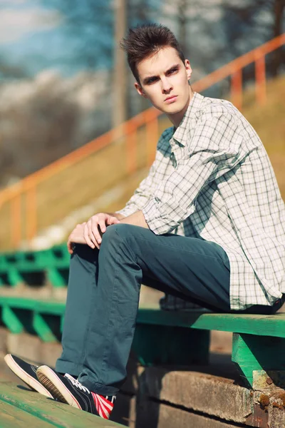 Free hipster man sitting on a bench in the city, sunny summer ev — Stock Photo, Image