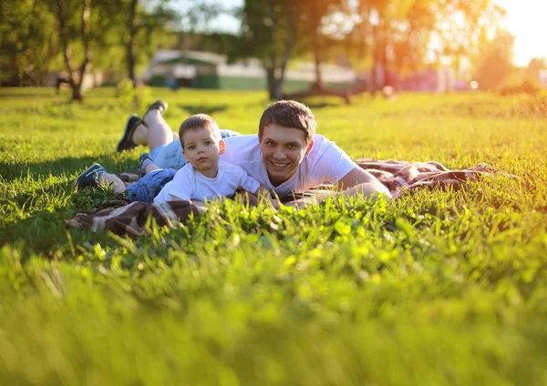 Szczęśliwy ojciec i syn zabawy leżąc na trawie w letnim słońcu — Zdjęcie stockowe