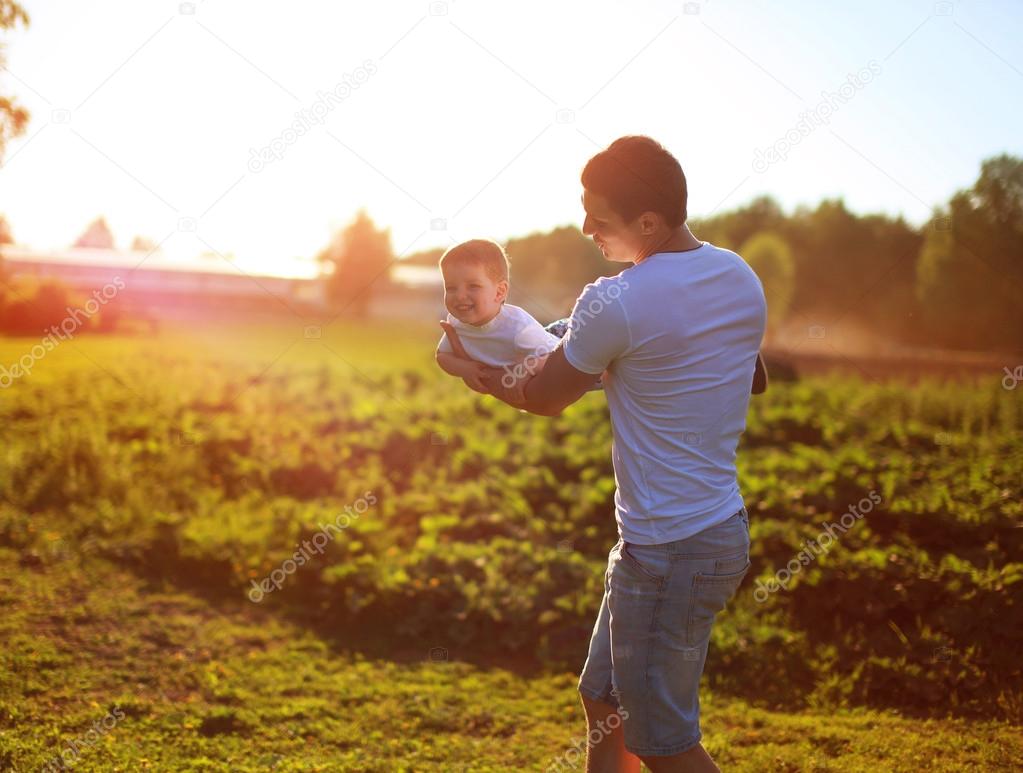 Happy child, dad and son having fun, holding on hands on a sunse
