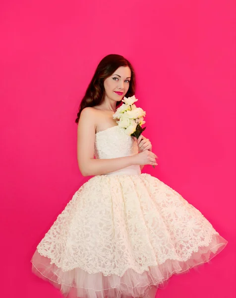 Cute girl in a wedding dress holding flowers — Stock Photo, Image