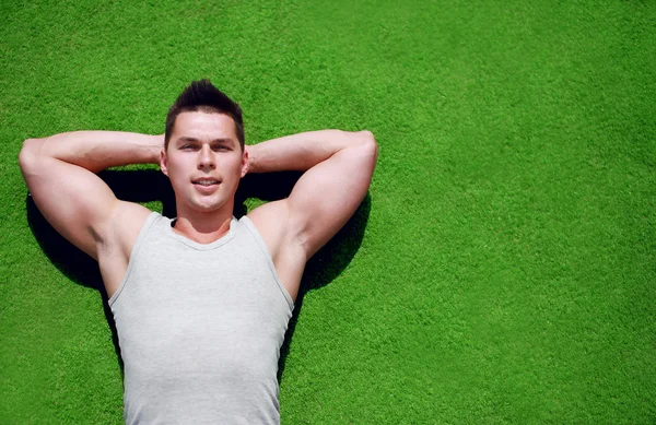 Fitness, sport - concept. Handsome man relaxing on the grass sum — Stock Photo, Image