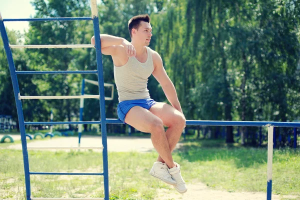 Street workout, handsome sporty guy on horizontal bars