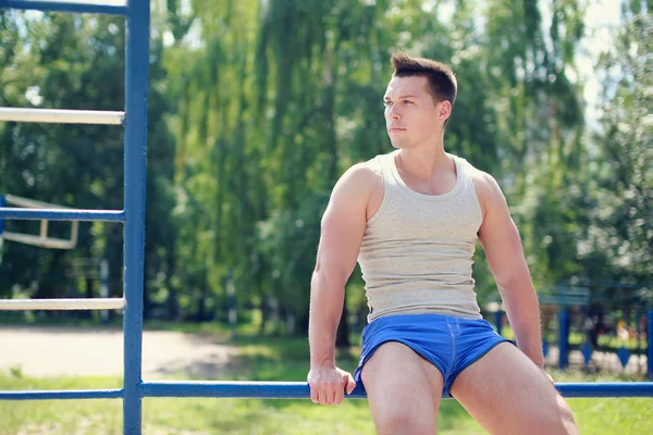 Street workout, sporty guy on horizontal bars