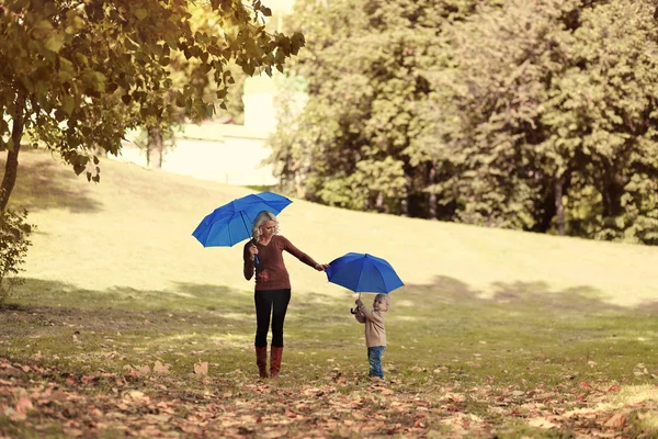 Madre y bebé con paraguas paseos en el parque de otoño al aire libre — Foto de Stock