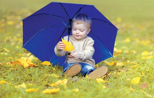 Carino bambino con ombrellone nel parco autunnale — Foto Stock