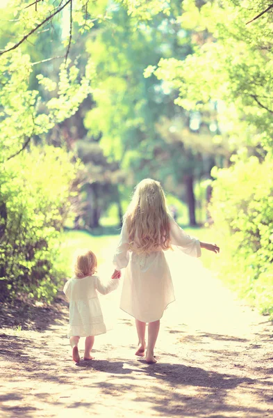 Sunny photo two little sisters holding hands walking barefoot in — Stock Photo, Image