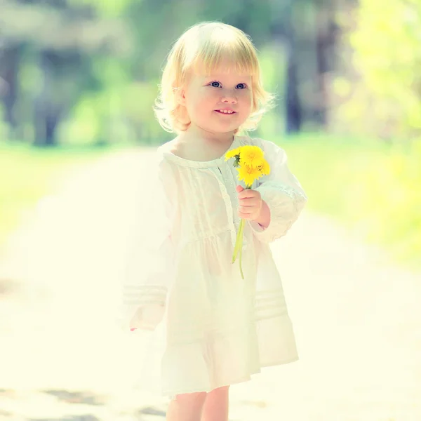 Retrato soleado de un niño lindo con diente de león amarillo en el día de verano — Foto de Stock