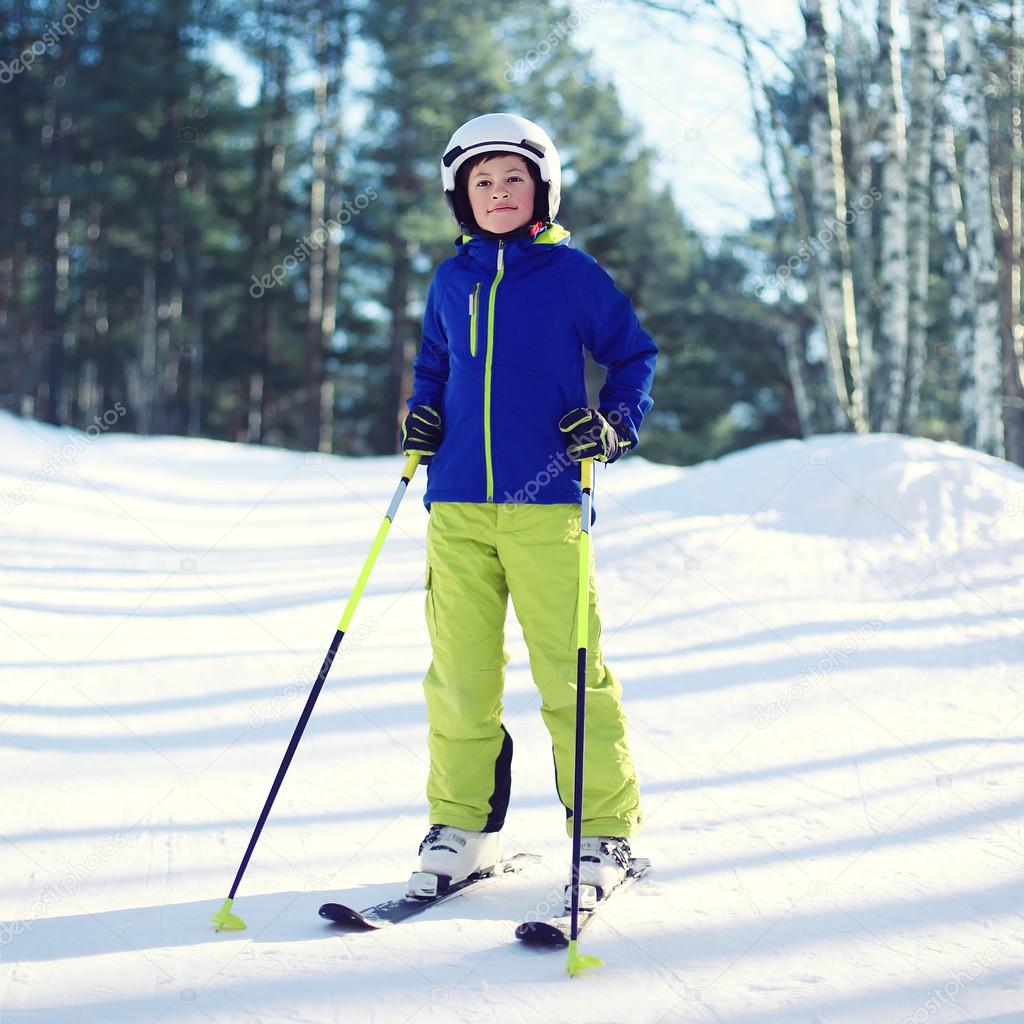 Professional skier boy in sportswear and helmet, sunny winter da