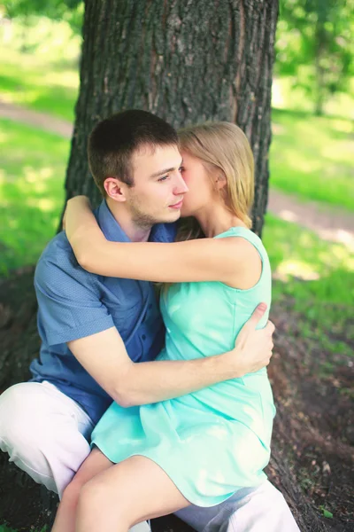 Mladý pár v lásce, muž a žena odpočívá nedaleko stromu seděl v — Stock fotografie