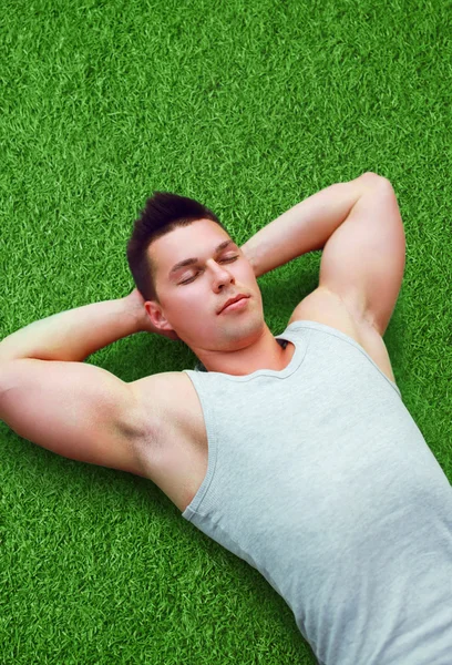 Portrait of handsome sporty fitness young man relaxing on the gr — Stock Photo, Image