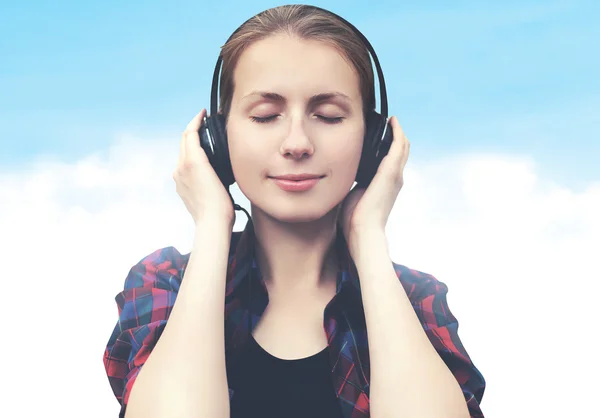 Portret van een jonge vrouw in hoofdtelefoon ontspant en luistert naar mus — Stockfoto