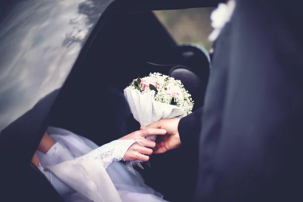 Brudgummen möter bruden från bilen med en bröllop bukett av flo — Stockfoto