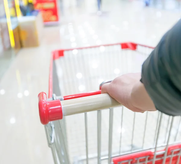 Hand and shopping trolley — Stock Photo, Image