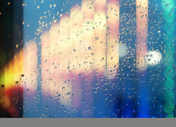 Мокрое окно на фоне ночного города — стоковое фото