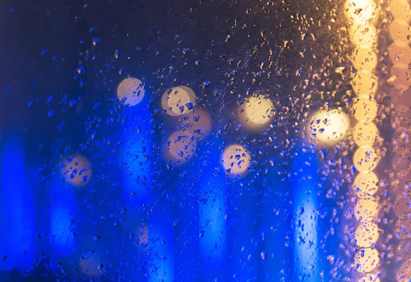 Мокрое окно на фоне ночи — стоковое фото