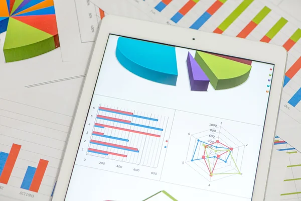 Gráficos financieros sobre la mesa con tableta — Foto de Stock