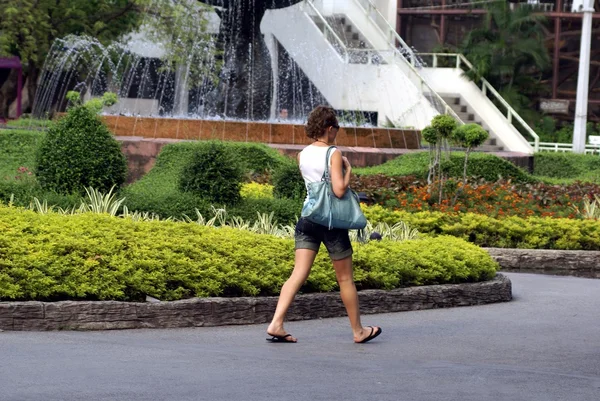 Vrouw uit koelen in een park naast een fontein — Stockfoto