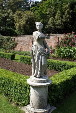 Statue of a woman holding a flower in a garden