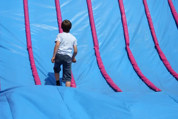 Criança que joga em uma corrediça inflável — Fotografia de Stock