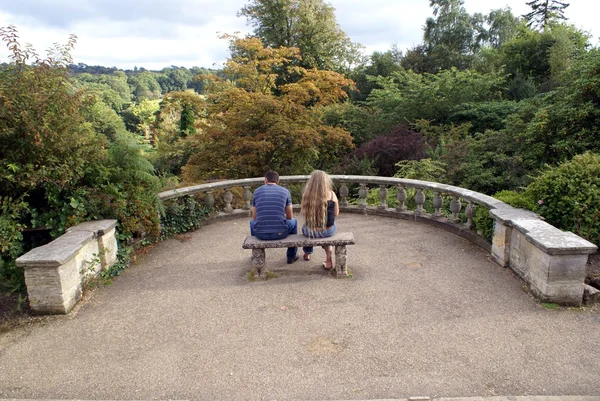 Para relaksujący na rzeźbione siedzenie w ogrodzie — Zdjęcie stockowe
