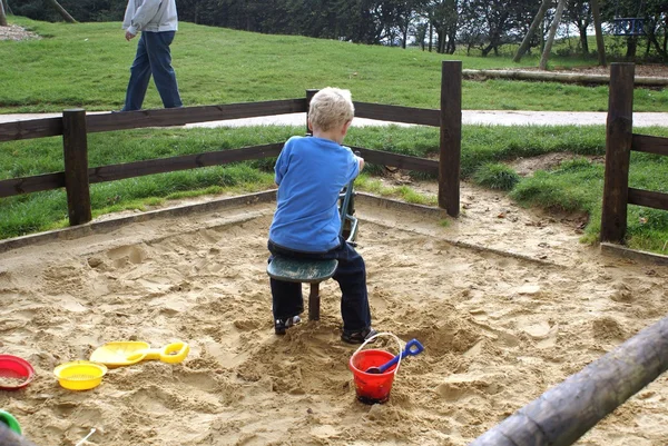 Menino brincando em um brinquedo em uma areia — Fotografia de Stock