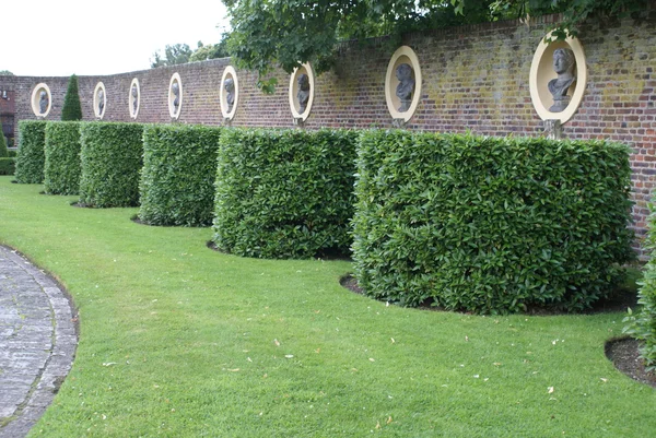 Yew topiary trees and statues in alcoves in a garden — Stock Photo, Image