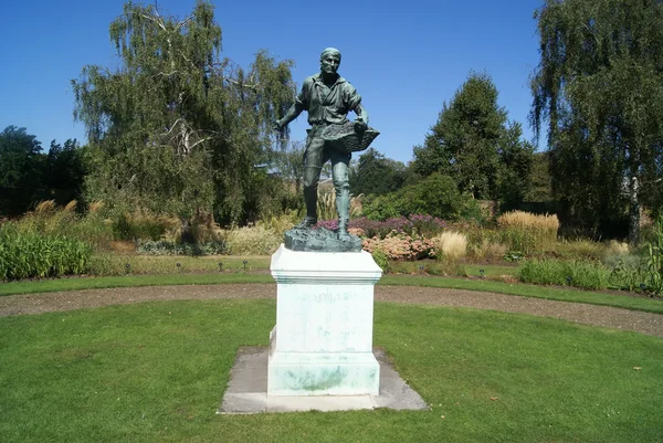 Standbeeld van een man die een mandje in een tuin. Tuinman standbeeld — Stockfoto