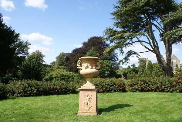 Gebeeldhouwde urn op een plint in een tuin — Stockfoto