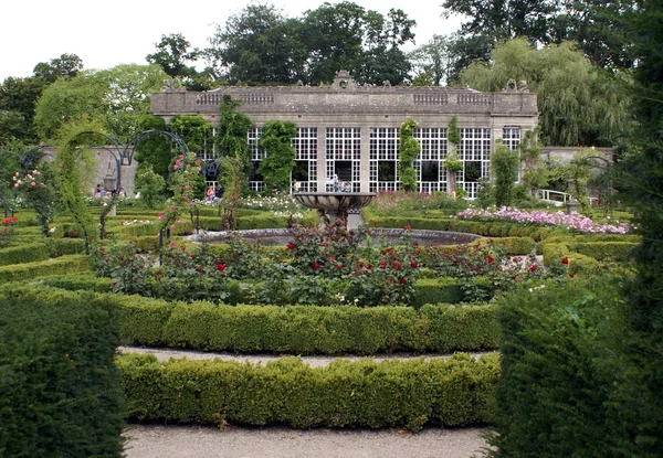 Jardim com uma fonte esculpida e arcos de rosa na forma de corações — Fotografia de Stock