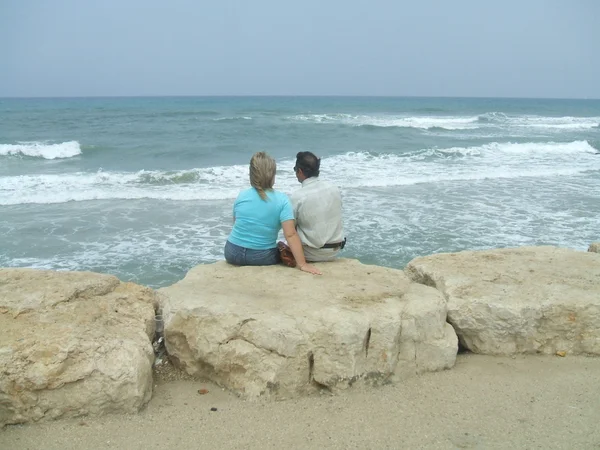 부부는 해변의 바위에 앉아 — 스톡 사진