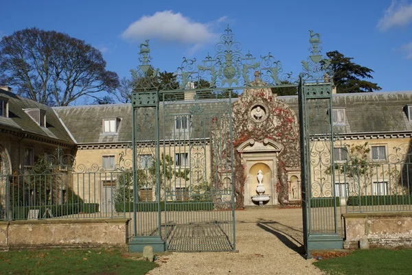 Decorative wrought iron gate and sculptured facade — Stock Photo, Image