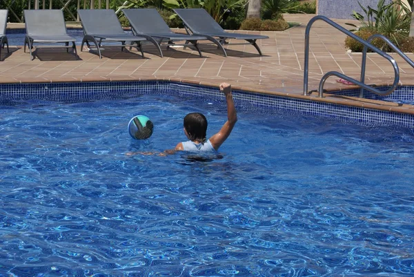 Child playing with a ball in a swimming pool — Stock Photo, Image