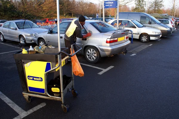 Cleaner washing or cleaning a car in a car park — Stock Photo, Image