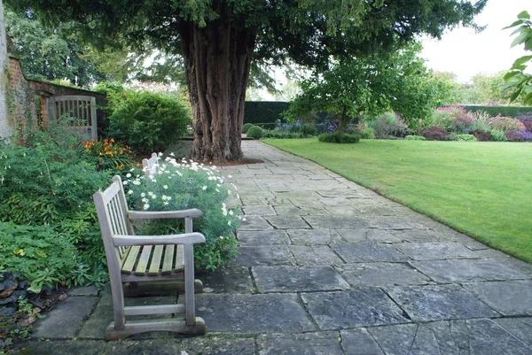 Banco de madera en un jardín. Asiento en un jardín — Foto de Stock