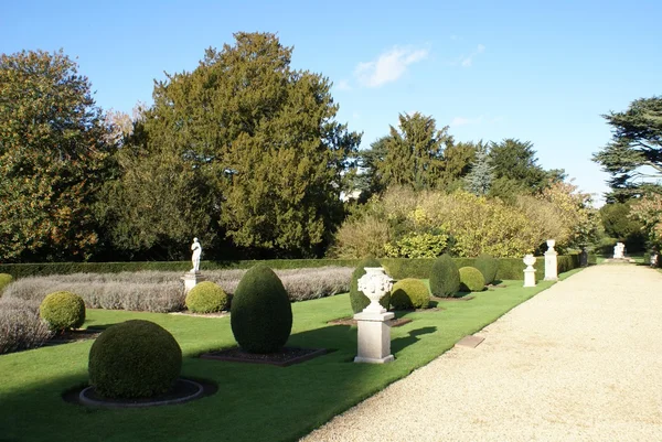 Topiary garden with urns and a statue — Stock Photo, Image