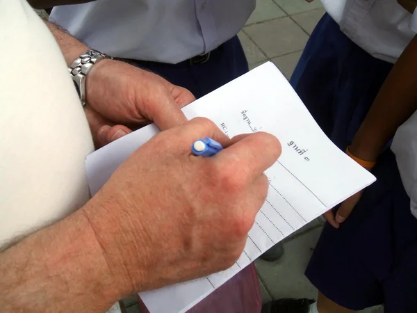hand of a man filling a form in Thai language