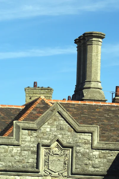 Old facade with coat of arms and chimneys — Stock Photo, Image