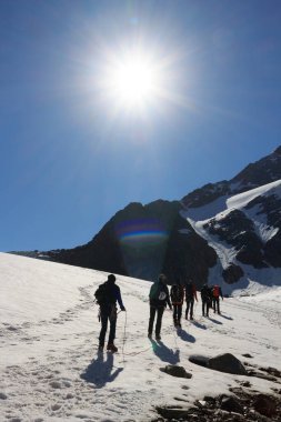 Halat ekibi buzul Taschachferner üzerinde kramponlarla dağcılık yapıyor ve Avusturya 'nın Tyrol Alplerinde mavi gökyüzü olan dağ kar panoraması