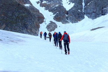 Halat ekibi, Avusturya 'nın Tyrol Alps kentindeki Wildspitze ve dağ kar panoramalarına doğru buzul Taschachferner üzerinde kramponlarla dağcılık yapıyor.
