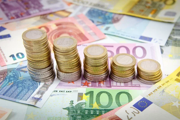 Rückgang der Stapel von Euro-Münzen auf Euro-Banknoten — Stockfoto