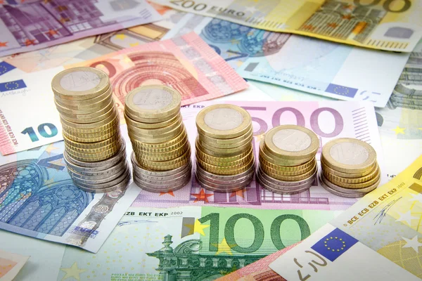Rückgang der Stapel von Euro-Münzen auf Euro-Banknoten — Stockfoto