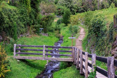 Hiking footpath, stream and signpost pointing towards village Algund, South Tyrol, Italy
