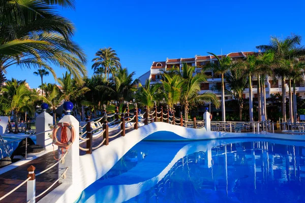 Playa de las Americas, Tenerife 'de yüzme havuzu, köprü ve palmiye ağaçları olan otel panoraması