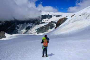 İtalya 'nın Pennine Alpleri' nde yaz aylarında kramponlar ve dağ buzulu manzaralı halat takımındaki dağcı.