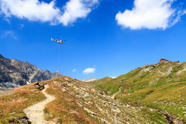 Transporthelikopter vliegen met leveringen en bergpanorama met alpenhut in Hohe Tauern Alps, Oostenrijk — Stockfoto